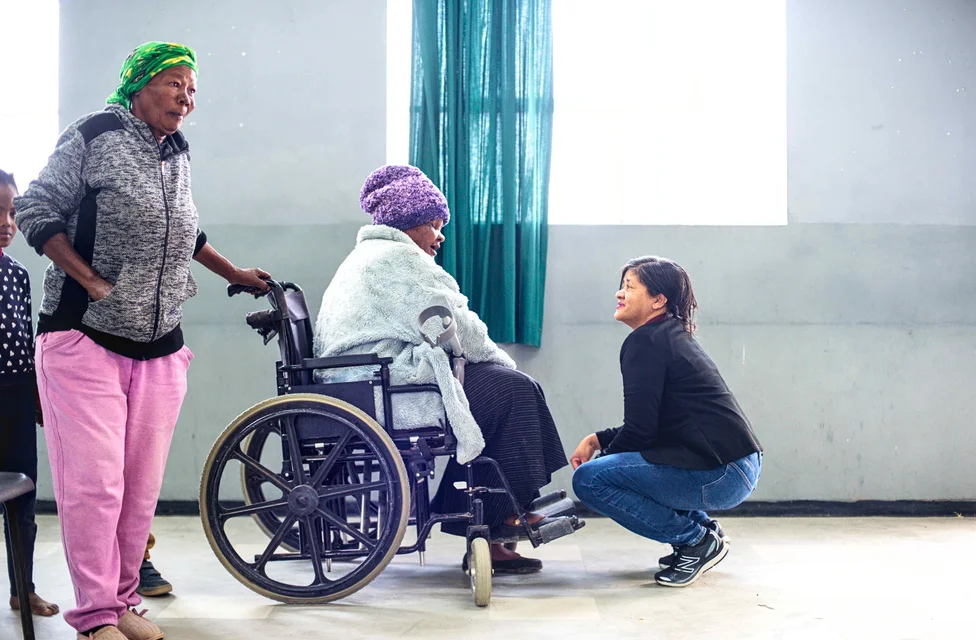 Lady in a wheelchair being assisted